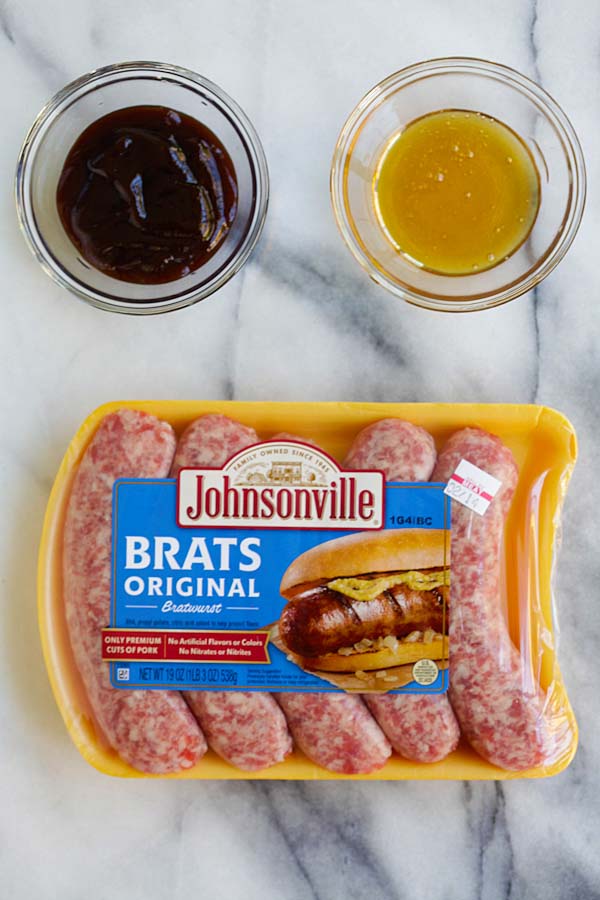 Johnsonville sausages and sides of honey sauce and barbecue sauce.
