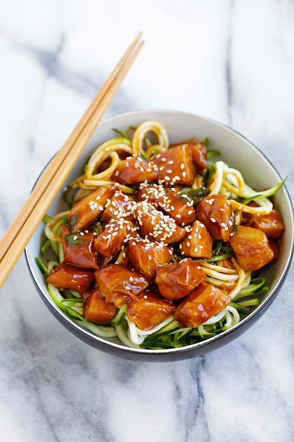 Easy and healthy zoodles with sweet and spicy honey sriracha chicken served in a bowl.