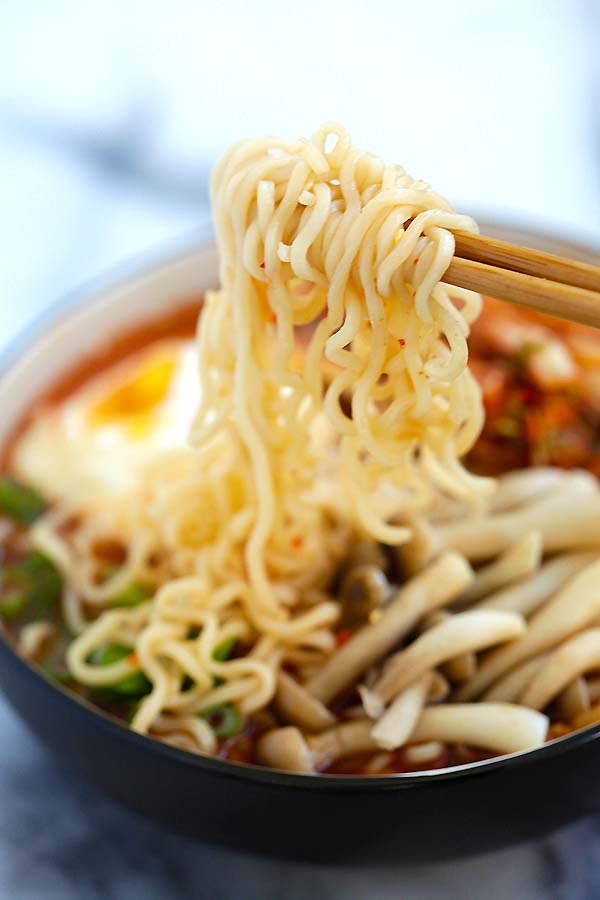 Close up kimchi ramen picked with a pair of chopsticks.