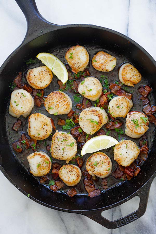 Top down view of seared scallops with crispy bacon bits sauteed in lemon butter sauce, ready to serve.