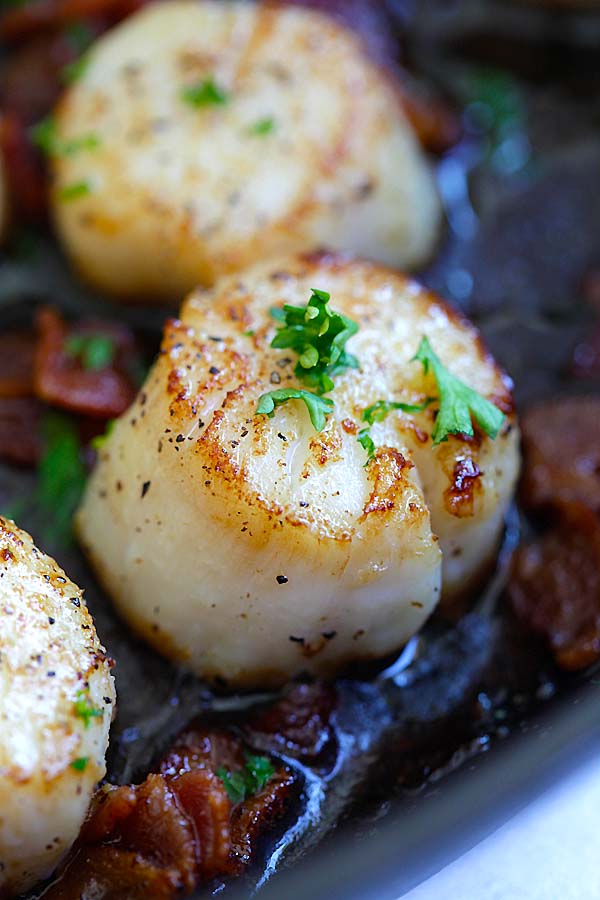 Close up easy seared scallops with crispy bacon bites in butter and lemon.