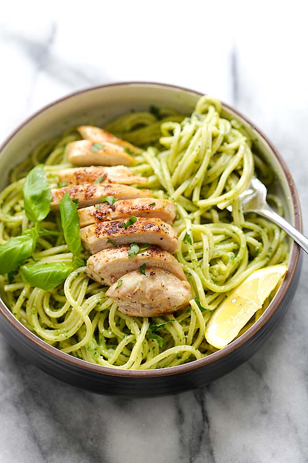 Easy and healthy pasta with basil pesto and sliced grilled chicken in a bowl.