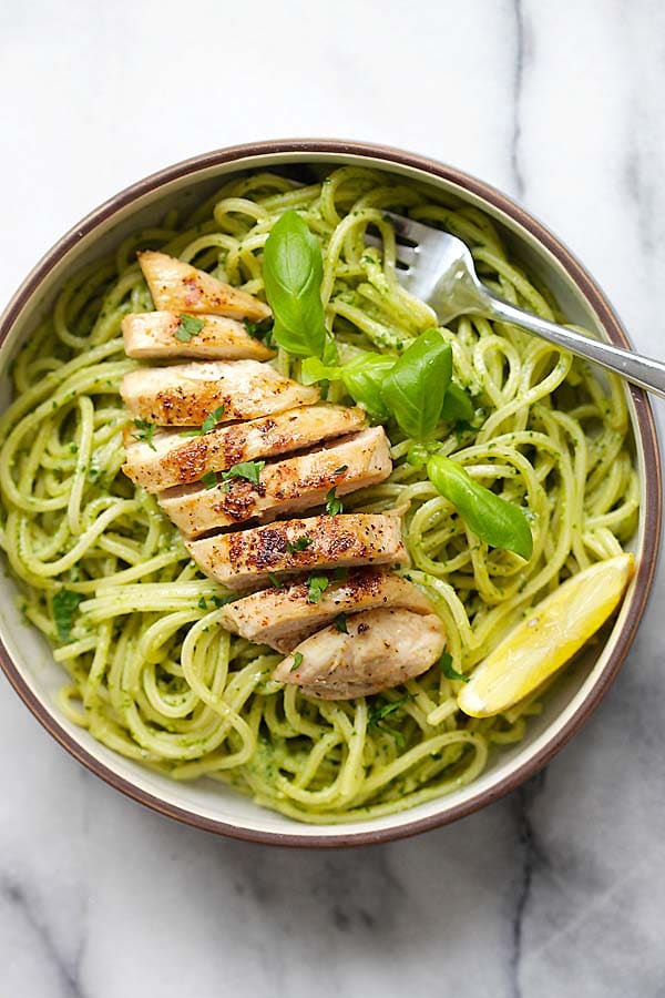 Easy and delicious homemade spaghetti pasta with basil pesto made with yogurt and Parmesan cheese and grilled chicken on top of it.