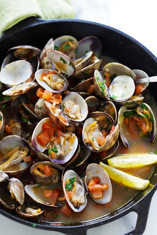 Italian sauteed clams with lemon and tomatoes, in a skillet.