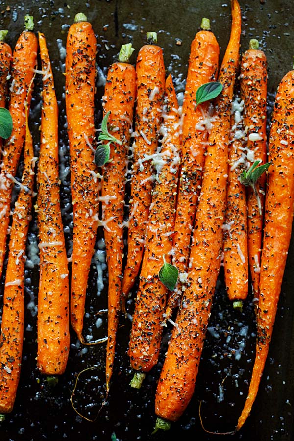 Healthy Italian oven-roasted carrots recipe with Italian seasonings, fresh herbs and Parmesan cheese in a baking tray.