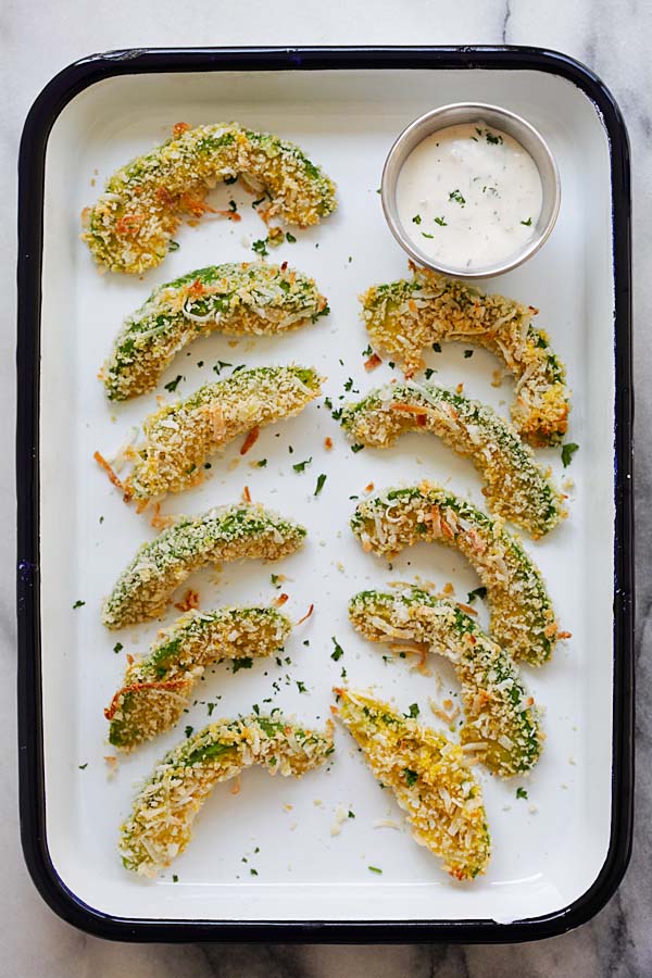 Easy healthy curry-flavored avocado snack aligned in baking tray with a side of ranch dressing sauce.