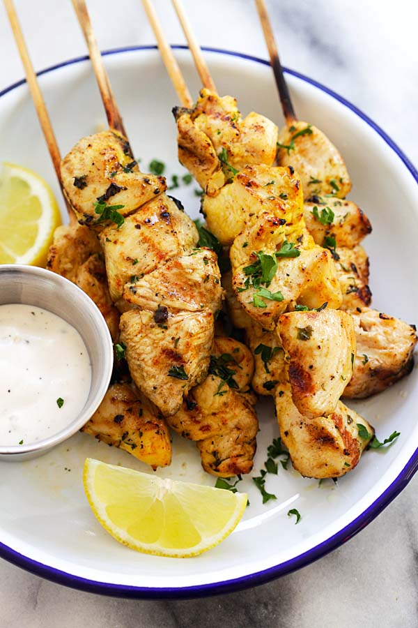 Easy and quick Greek chicken souvlaki skewers, served in a plate, with a side of ranch dipping sauce.