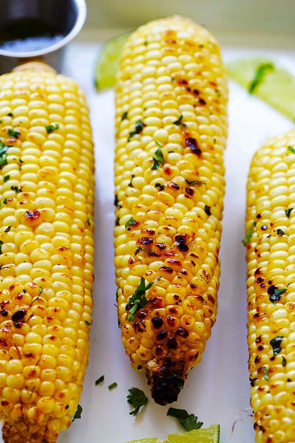 Close up grilled corn coated with honey butter cilantro lime sauce.