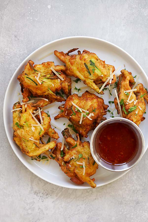 Easy and quick vegetable zucchini fritters, with a side of sweet chili dipping sauce, served in a plate.