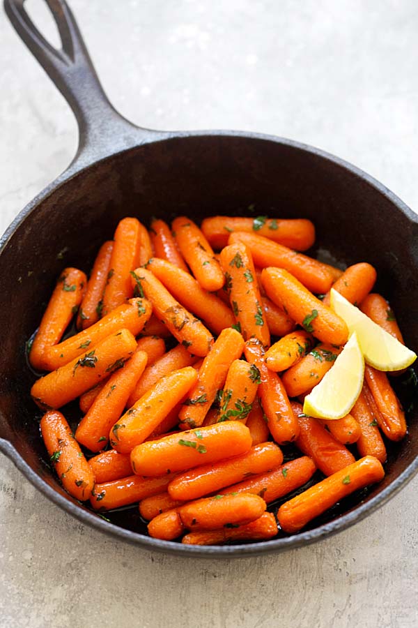 Easy healthy roasted baby carrots in a sweet and spicy honey sriracha sauce, in a skillet.