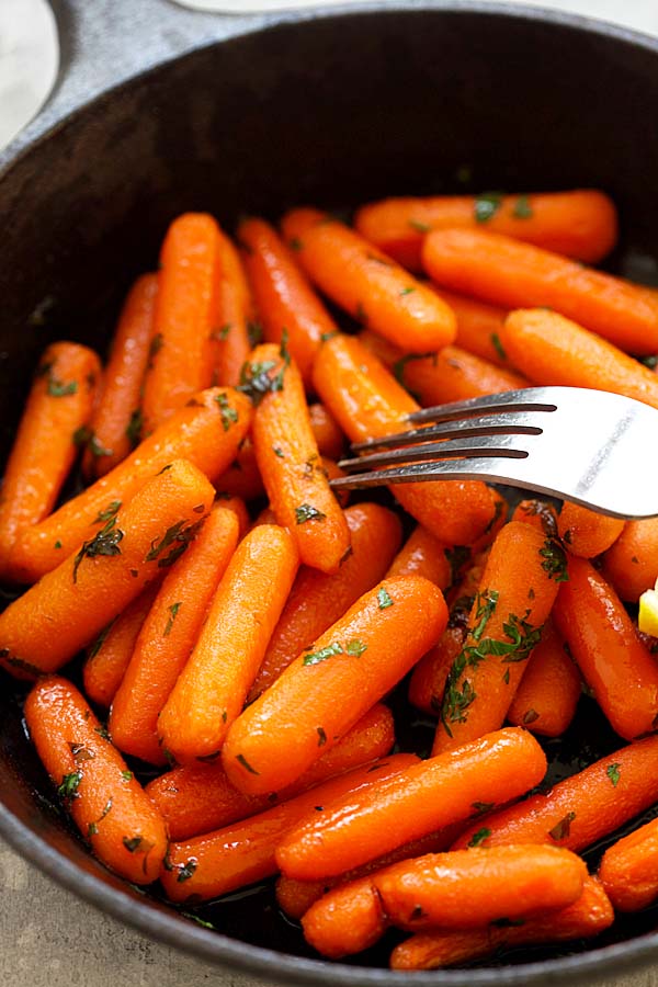 Easy roasted baby carrots in a sweet and spicy honey sriracha glaze in a skillet.