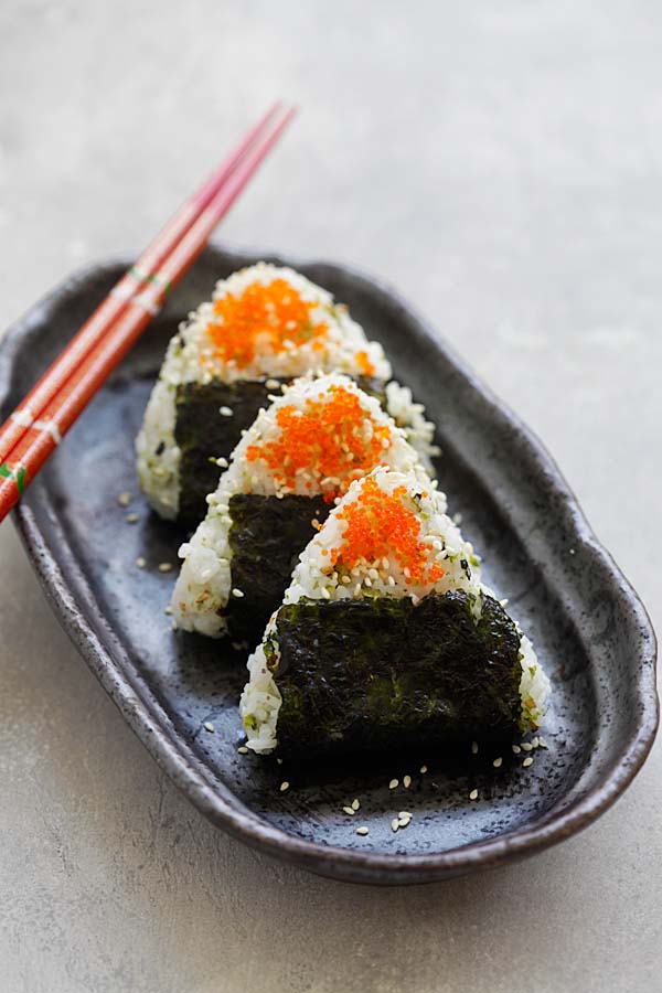 Homemade Onigiri topped with orange masago served in a serving dish.