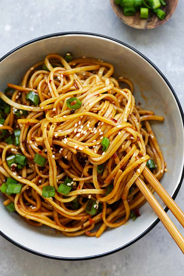 Sichuan Cold noodles in a spicy, savory and numbing Szechuan sauce with a pair of wooden chopsticks.