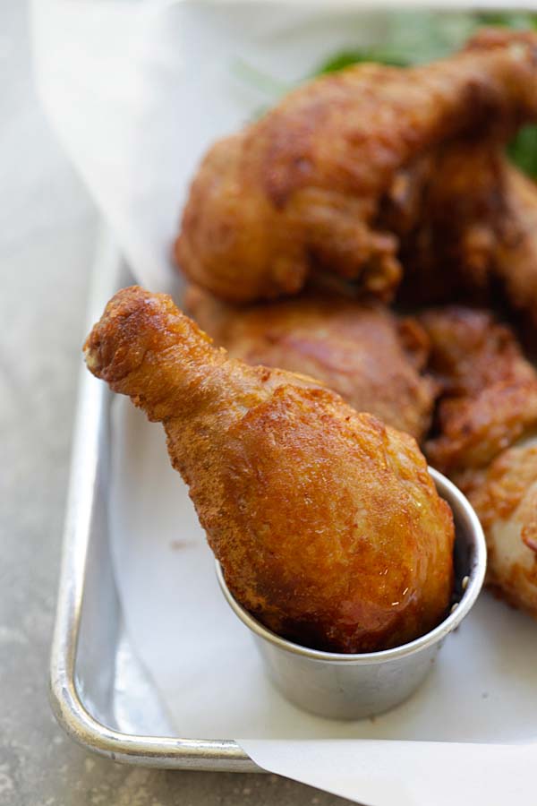 Belacan fried chicken drumstick dipped into a side of dipping sauce.