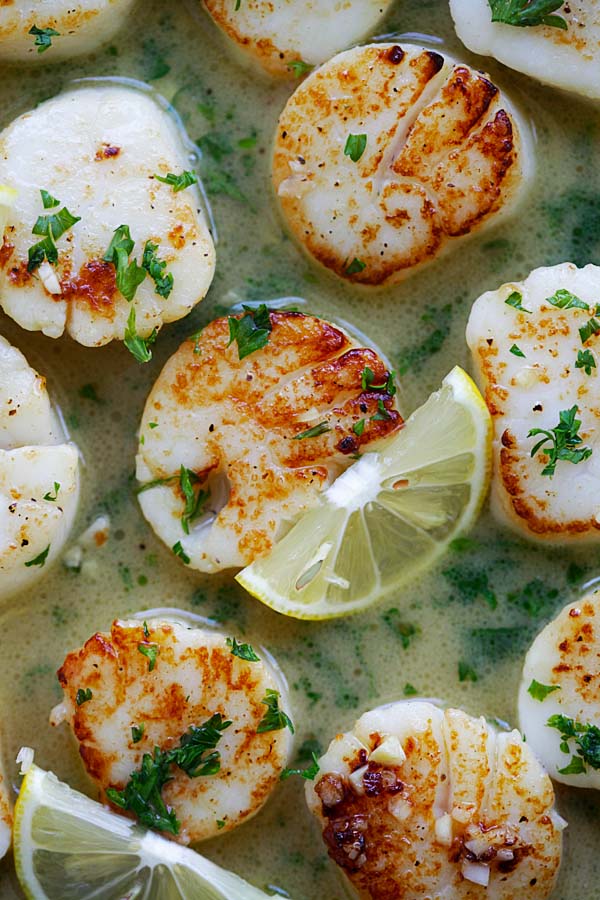 Close up garlic butter scallops with lemon sauce in a skillet.