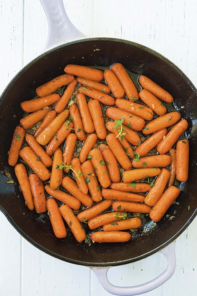Easy and quick oven roasted carrots with maple syrup, brown butter and garlic herb in a skillet.