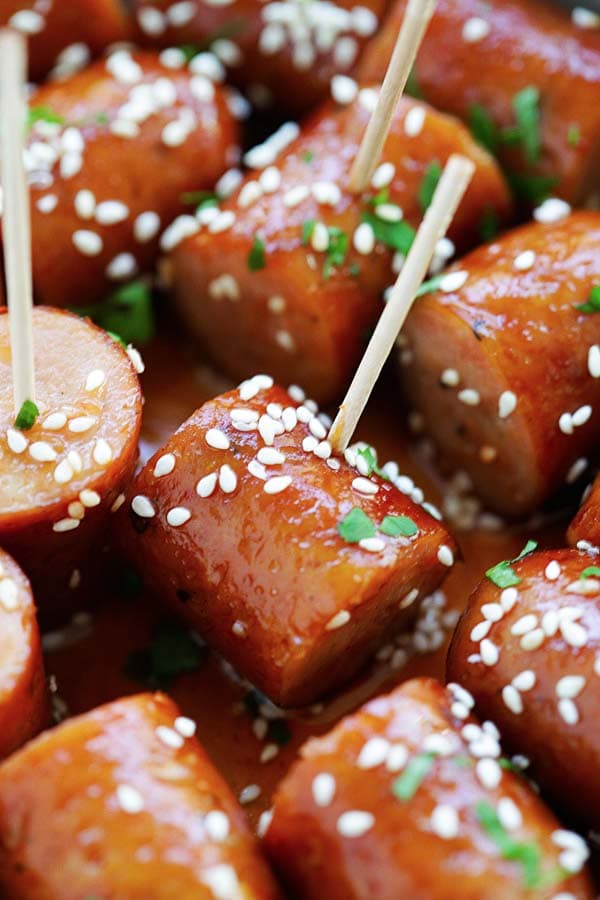 Honey Sriracha Sausage Bites garnished with chopped parsley and sesame seeds, served in a serving dish, ready to serve.