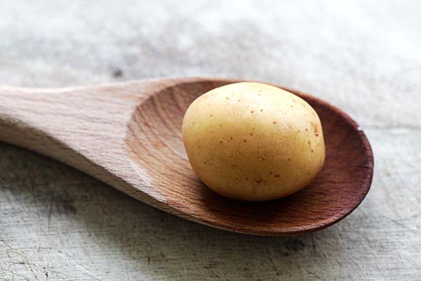 Cutting hasselback potatoes on a wood ladle