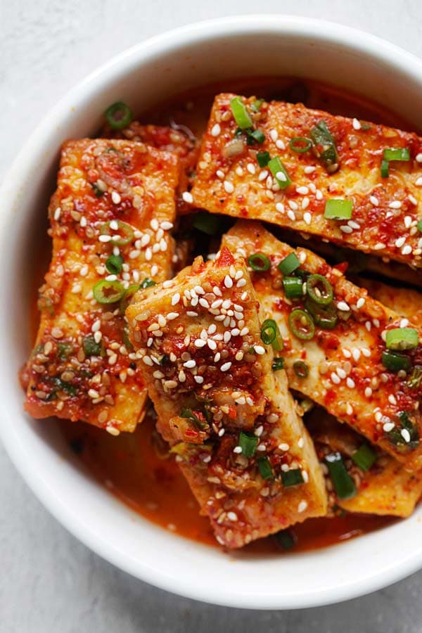 Korean braised tofu topped with sesame seeds and chopped scallion (side dish) in a bowl ready to serve.