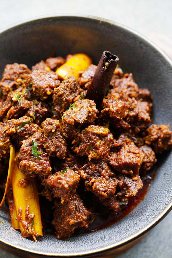 Close up photo of beef rendang recipe with tender beef cubes coated with dark brown rendang sauce. 