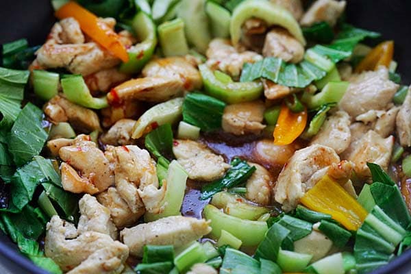 Stir frying chicken and vegetables in a pan.