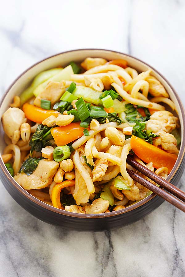 Blue Apron Stir-Fry Chicken with chewy udon noodles with tender chicken and sauteed peppers and bok choy in a bowl with a pair of chopsticks.