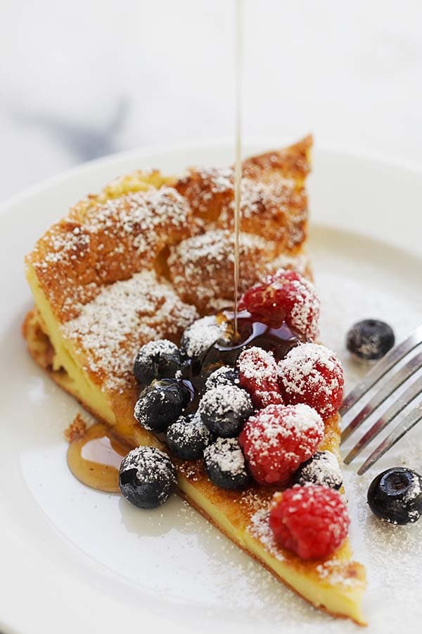 A slice of Dutch baby pancake served with maple syrup.