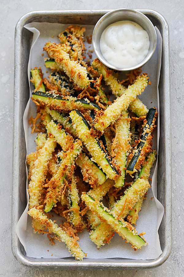 Healthy baked zucchini fries made with Japanese panko bread crumbs and Parmesan cheese in a silver ware.