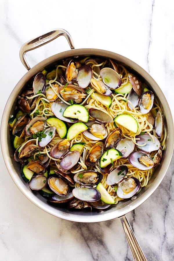 Easy spaghetti pasta with clams and zucchini, white wine, olive oil, butter and garlic in a skillet.