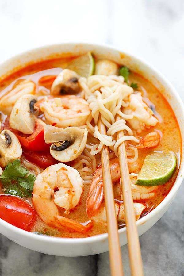Quick and easy Thai Tom Yum soup noodles made with shrimp, mushrooms, herbs and tomatoes in a bowl with chopsticks.