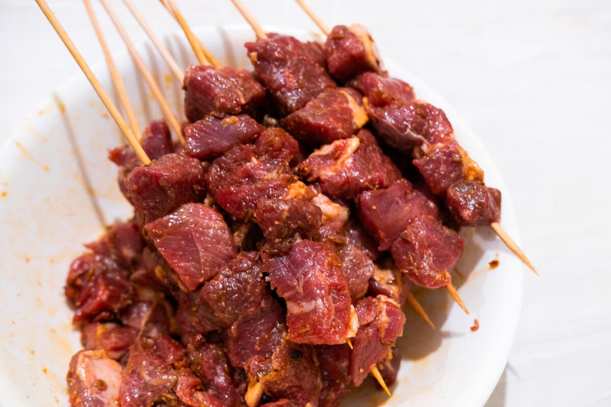 Skewers of marinated lamb cubes on a plate.