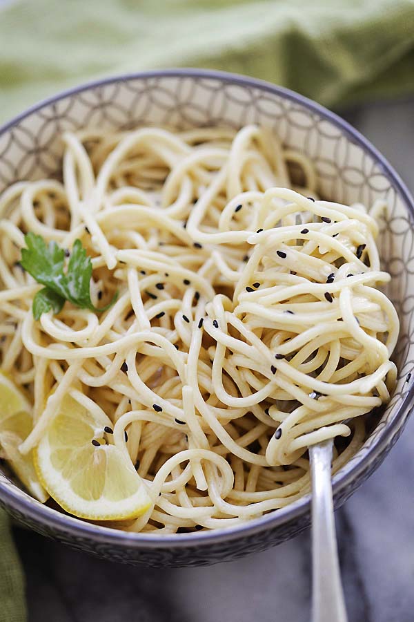 Asian noodles tossed with creamy sesame sauce, served in a bowl with a fork.