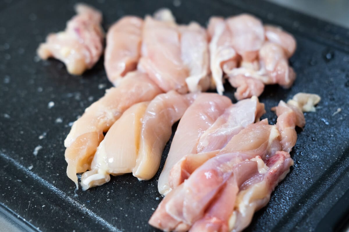 Sliced chicken thighs on a chopping board. 