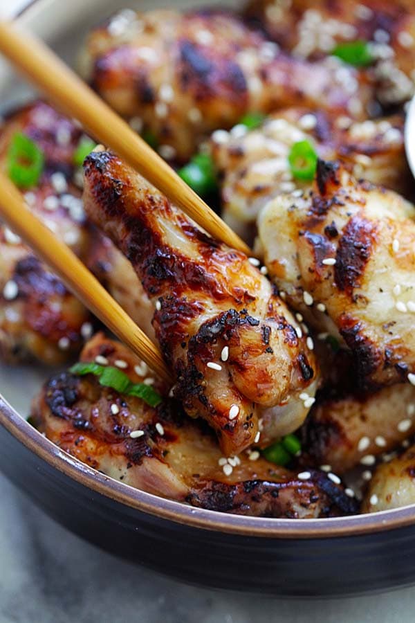 Five spice grilled chicken wings picked with a pair of chopsticks.