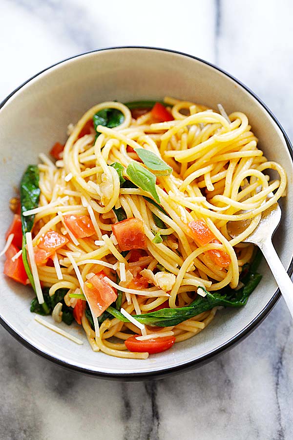 Close up of pasta with spinach and tomatoes.