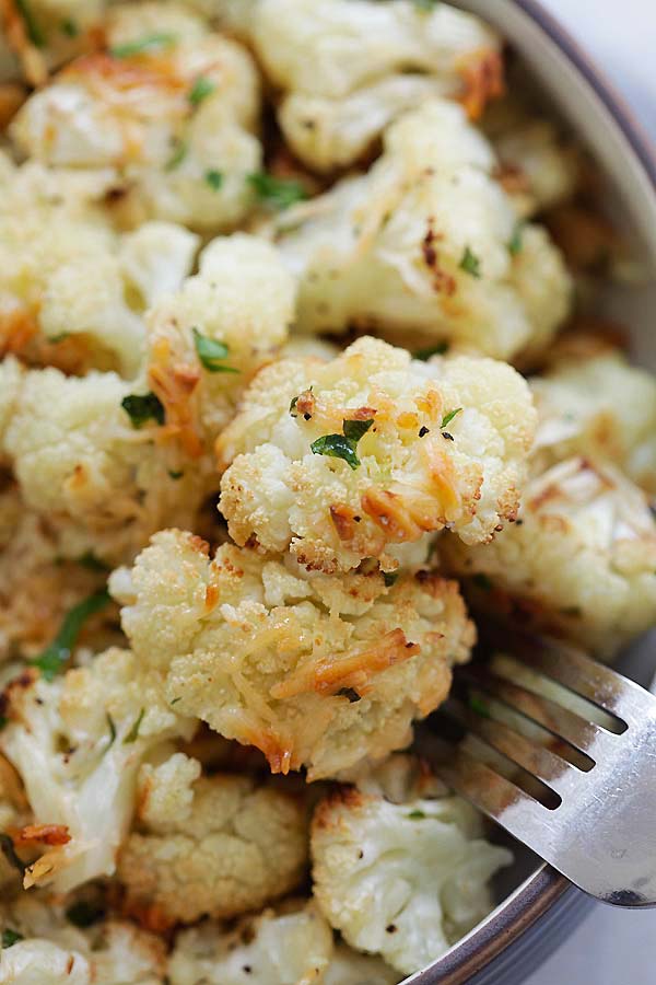 Oven-roasted cauliflower florets with garlic and Parmesan cheese, with a fork.