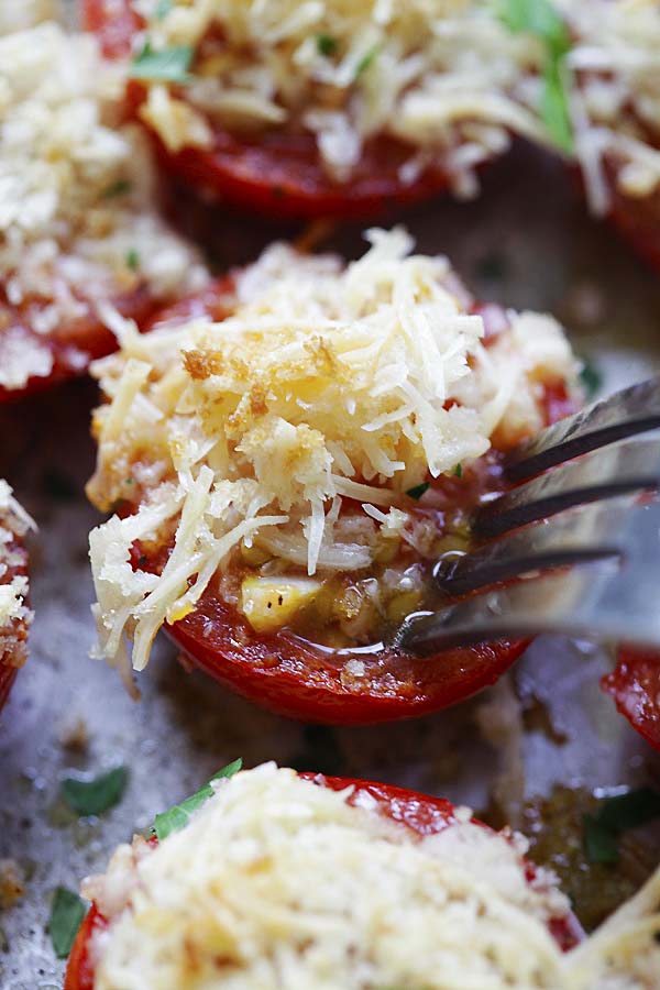 Close-up of garlic parmesan baked tomatoes poked with a fork.