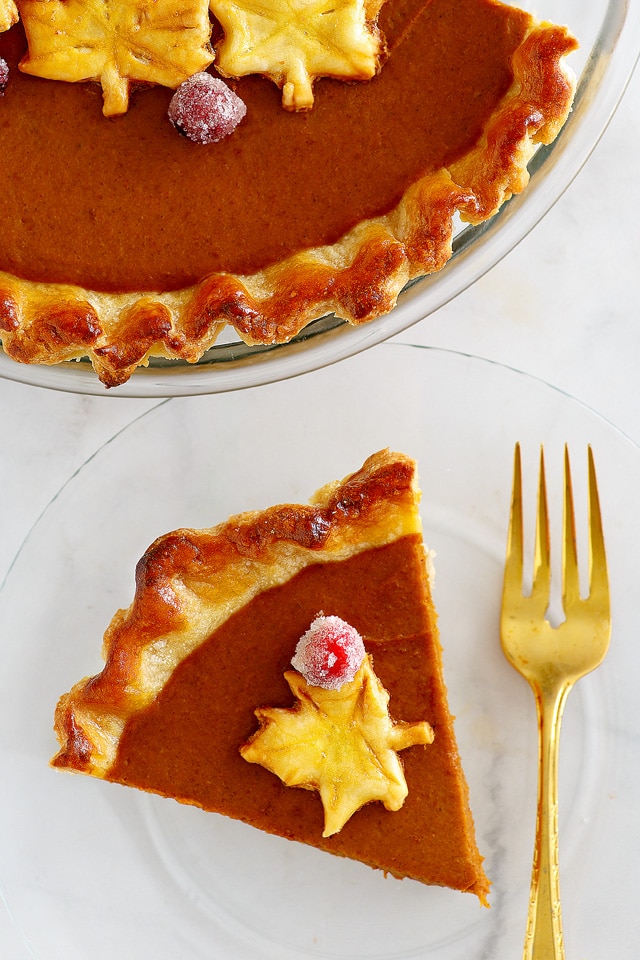 Pumpkin pie on a serving plate, with a fork and ready to be eaten.