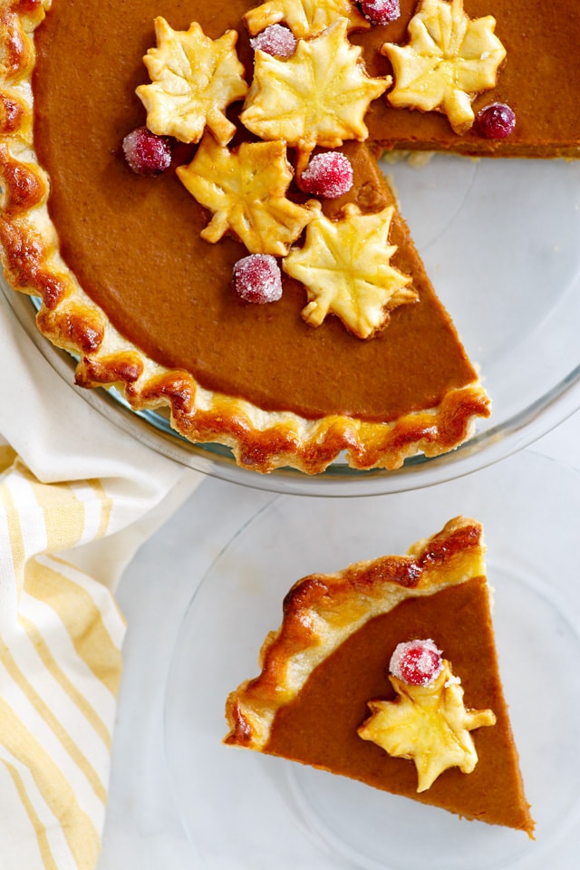 A slice of pumpkin pie with autumn leaf decoration, ready to be served.