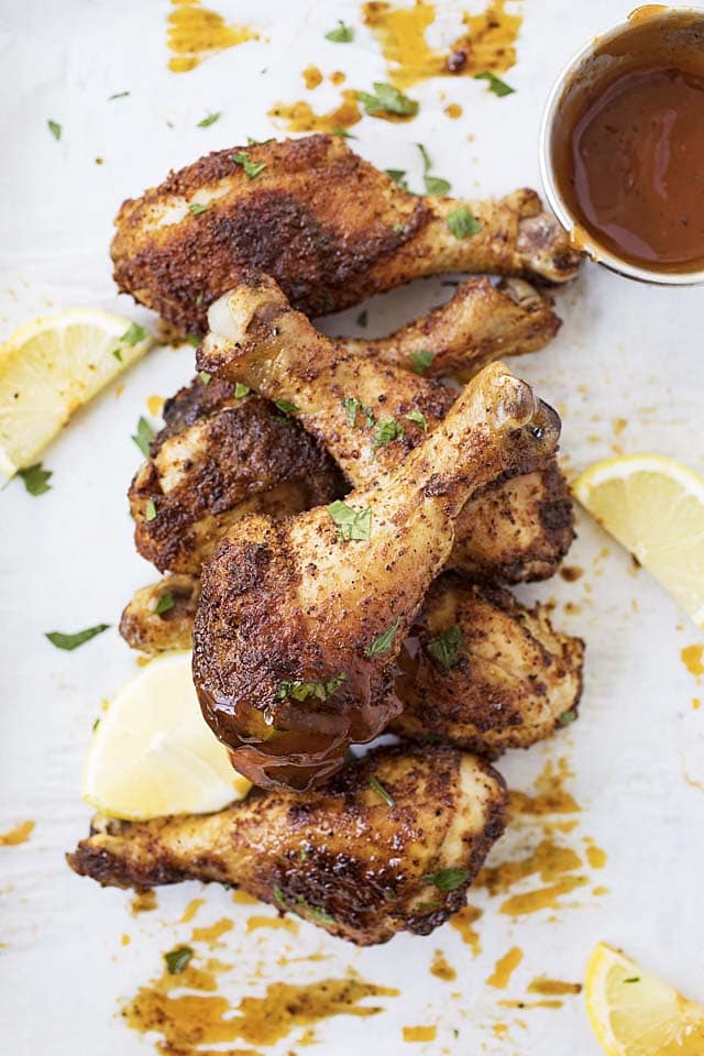 Baked chicken drumsticks served with a side of BBQ dipping sauce.