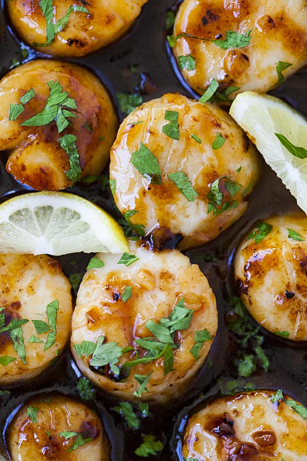 Close up of honey garlic scallops, topped with chopped parsley.