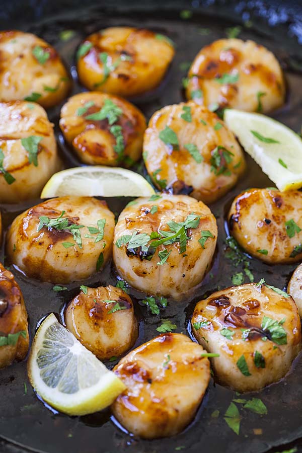 Scallops in a skillet with honey garlic sauce.