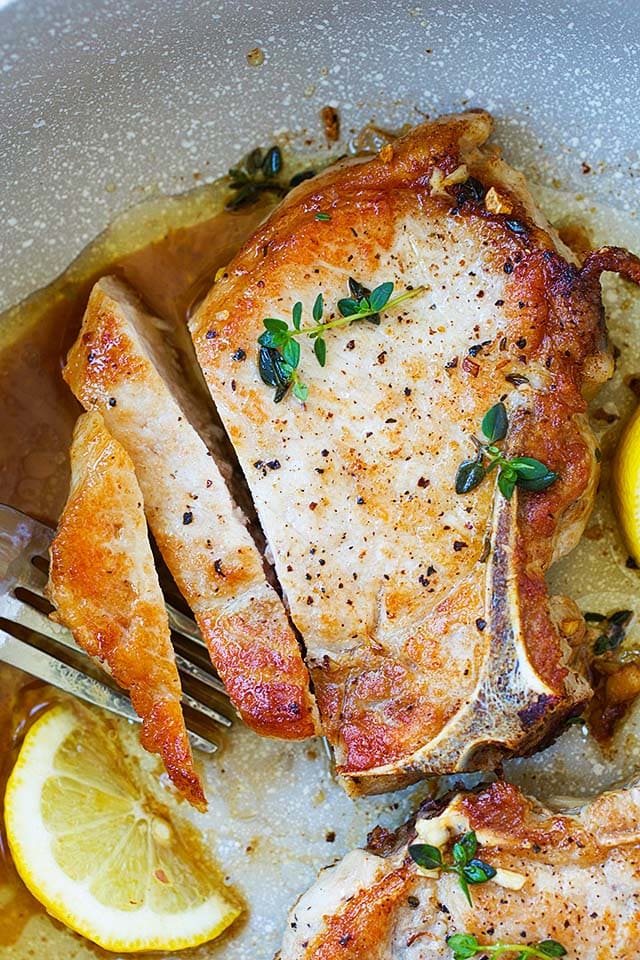 Pork chops on stove with garlic butter sauce cooked in a skillet.