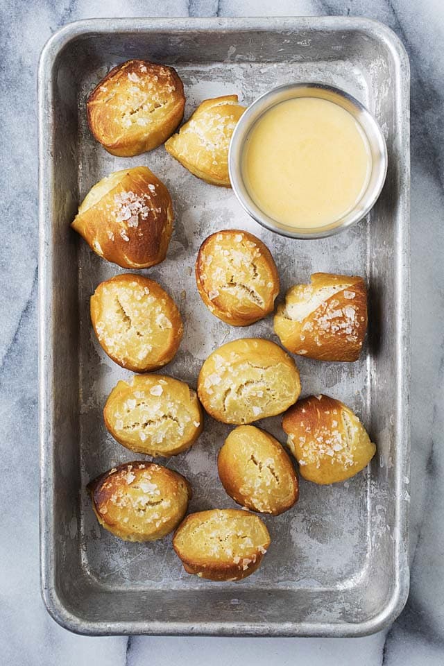 Easy and quick Pretzel Bites in a baking tray, served with a side of cheddar cheese sauce.