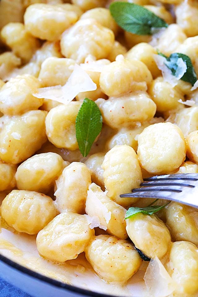 Soft and creamy potato gnocchi in garlic sauce, topped with shaved Parmesan cheese, ready to be served.