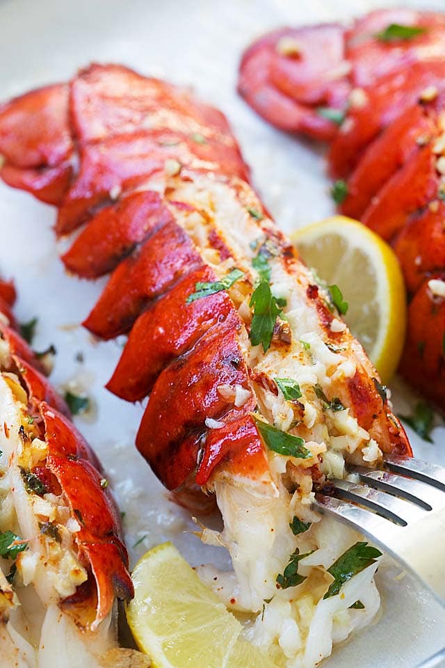Garlic butter broiled lobster tail poked with a fork.