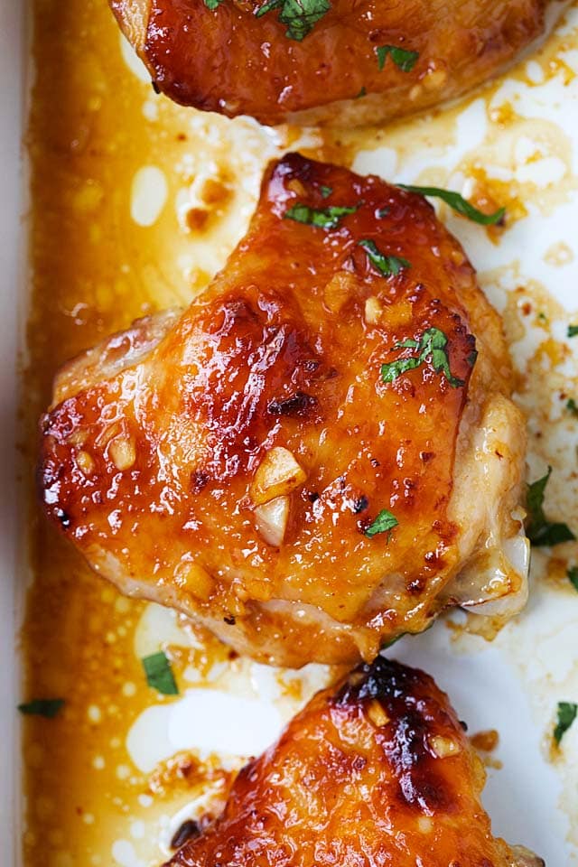 Closed up baked chicken thigh with golden honey garlic glaze sauce.