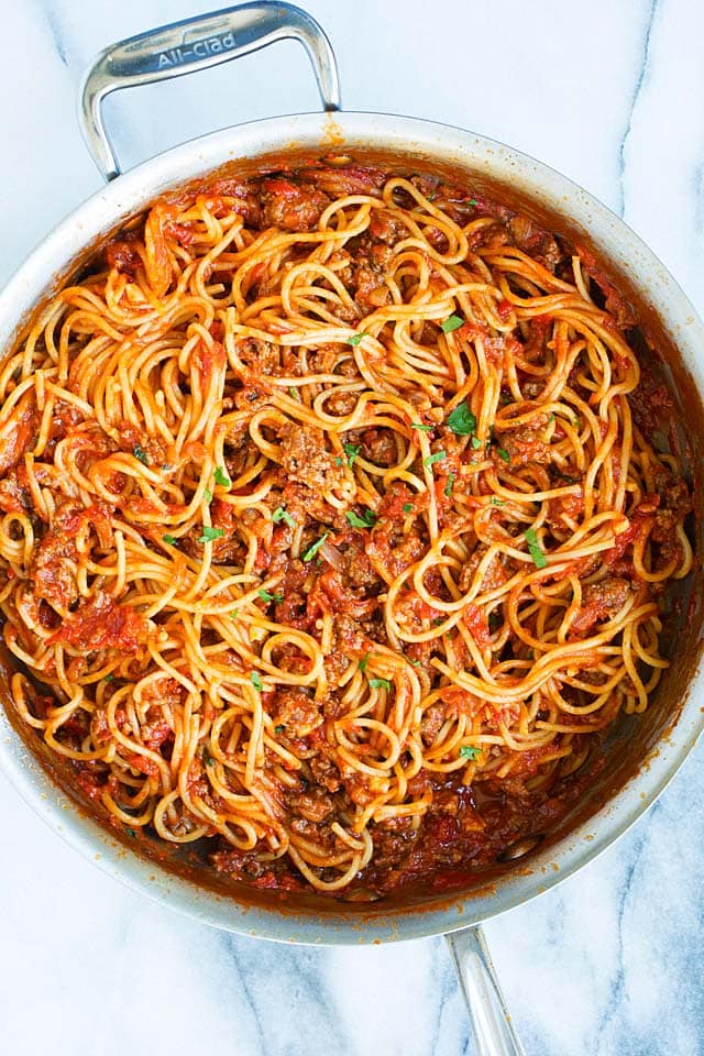 Top down shot of one pot spaghetti with meat sauce, topped with chopped parsley.