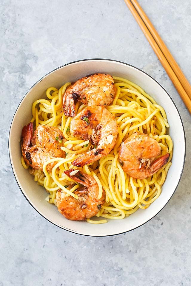 Shrimp garlic noodles, served in a bowl, with a pair of chopsticks.