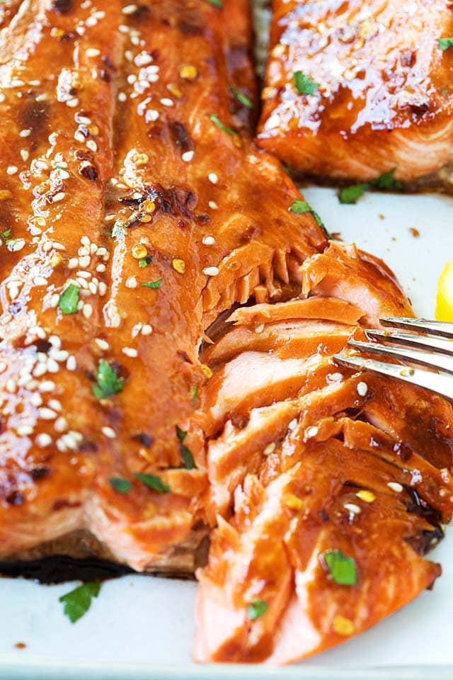 Flaking cooked salmon fillet with a fork.